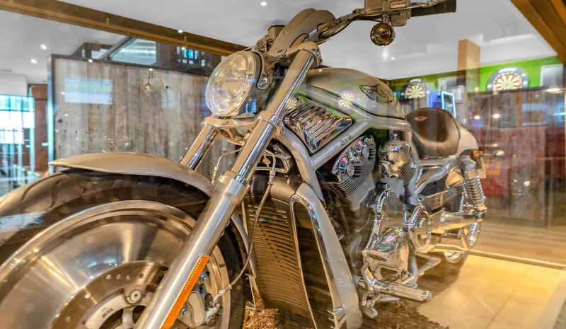 Customised motorcycle on display inside a sports bar with pool tables and dartboards visible in the background.