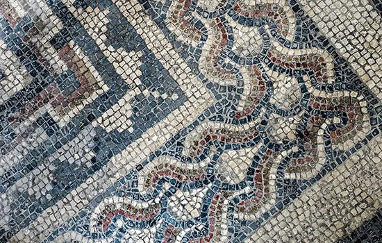 Close-up of intricate Roman mosaic floor with geometric and decorative patterns in coloured tesserae.