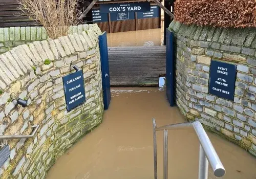 Stone entrance gateway flooded with muddy water, blocking access to venue.