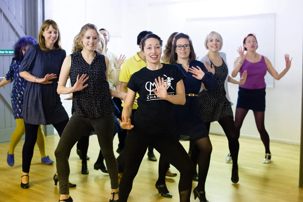 A group of women dancing together in a studio during a Charleston dance class.