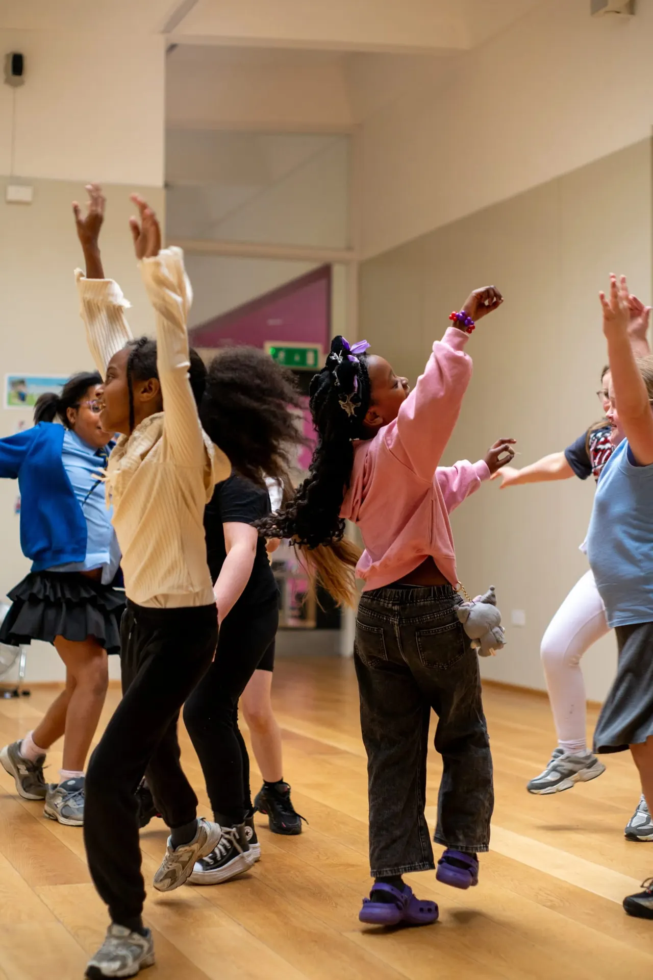 Group of children dancing and celebrating together in a studio space with arms raised.