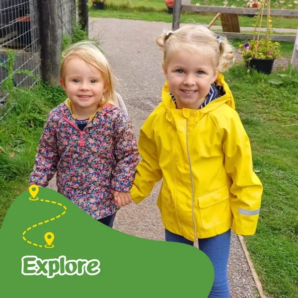 Two young children holding hands on a path at a farm or country venue.