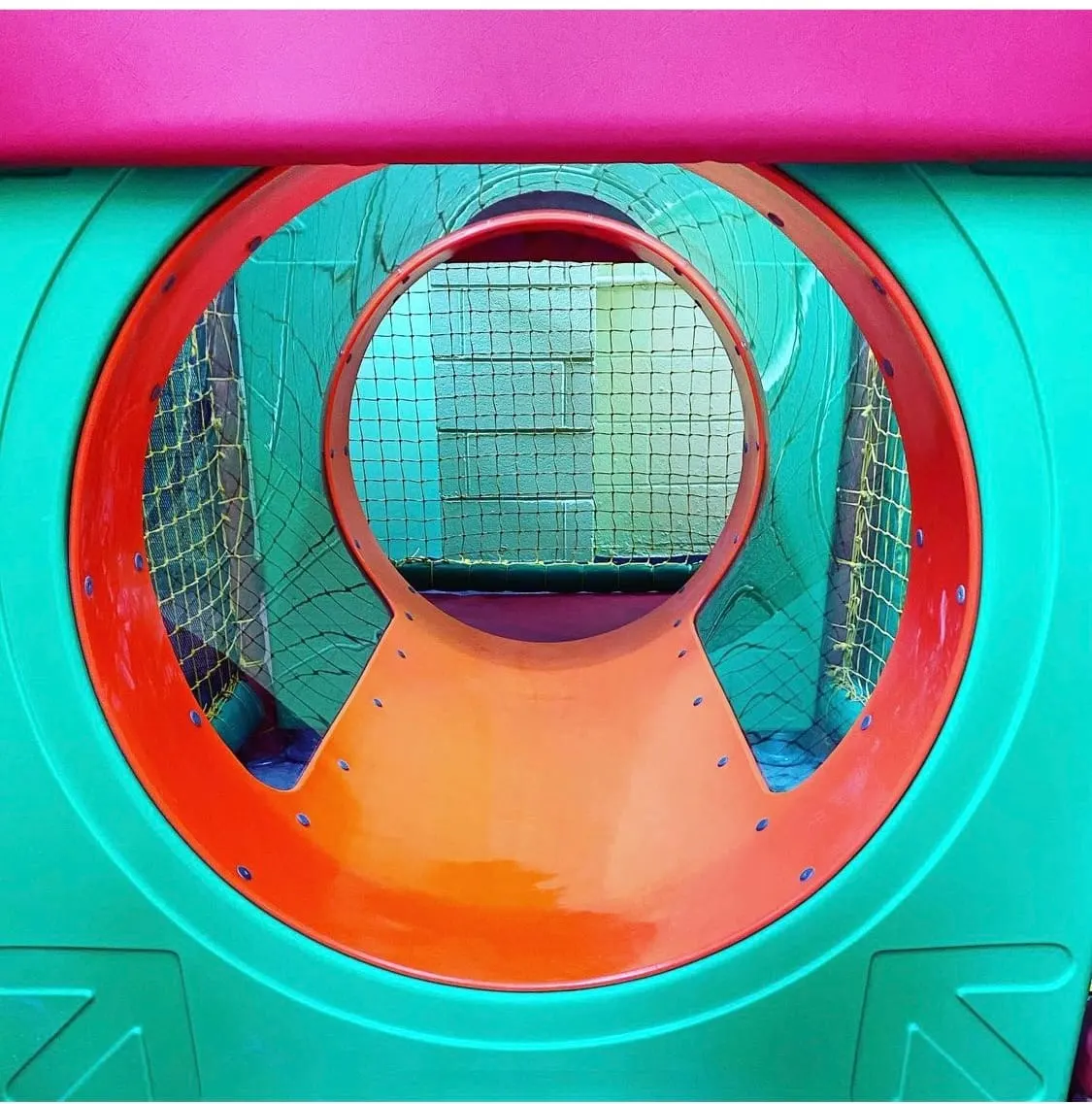 Colourful play tunnel with red and orange circular opening and turquoise walls, featuring mesh netting sides.