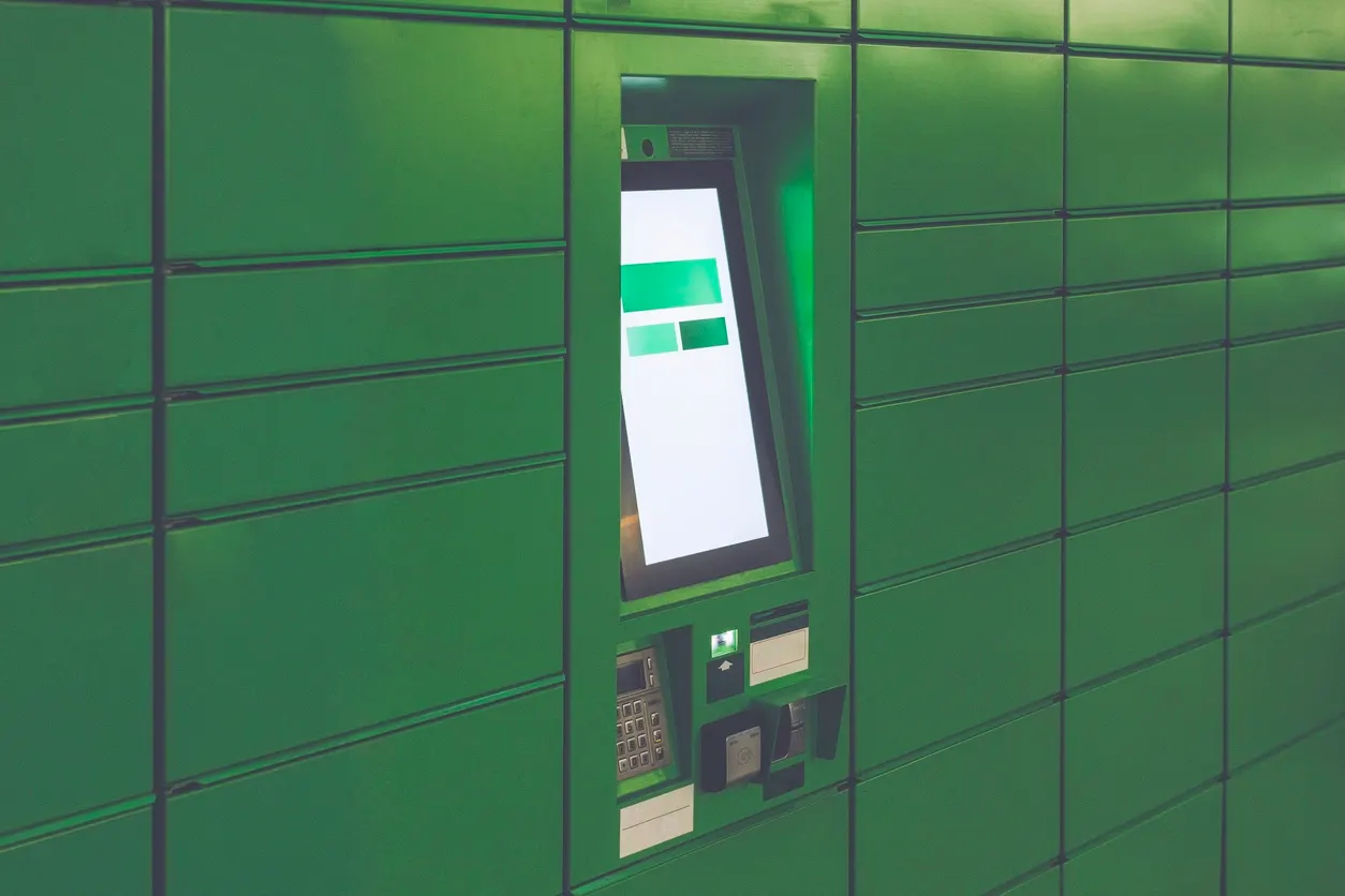 Payment terminal mounted on bright green tiled wall with blank display screen.