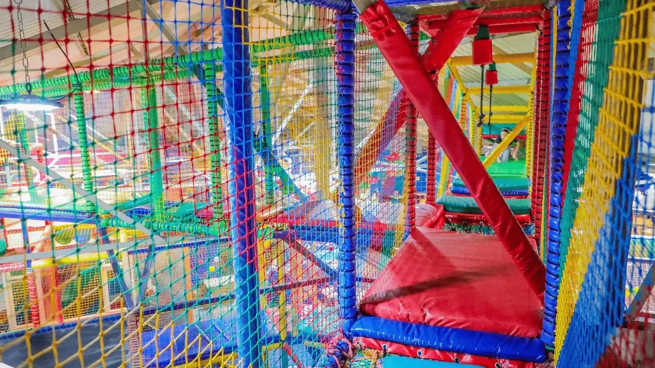Colourful soft-play indoor activity centre with interconnected tunnels, slides and padded structures in primary colours.