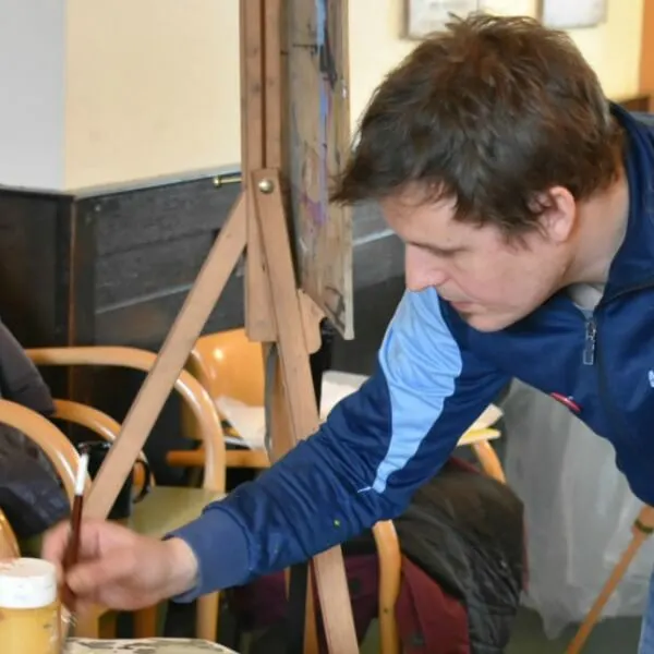 Young man concentrating whilst working on a loom during a weaving or textile craft activity.