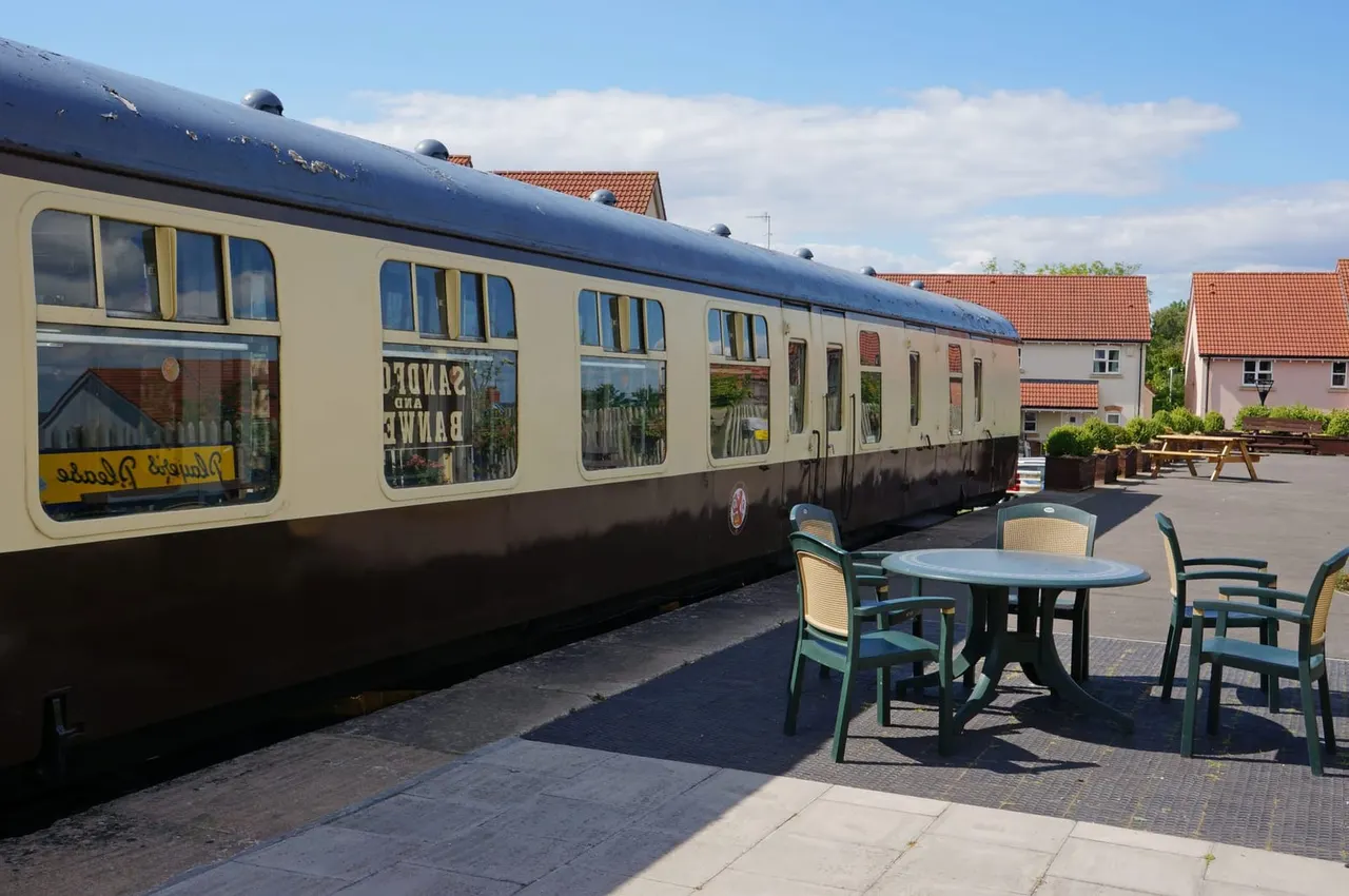 Converted railway carriage venue with outdoor seating area and traditional brick buildings.