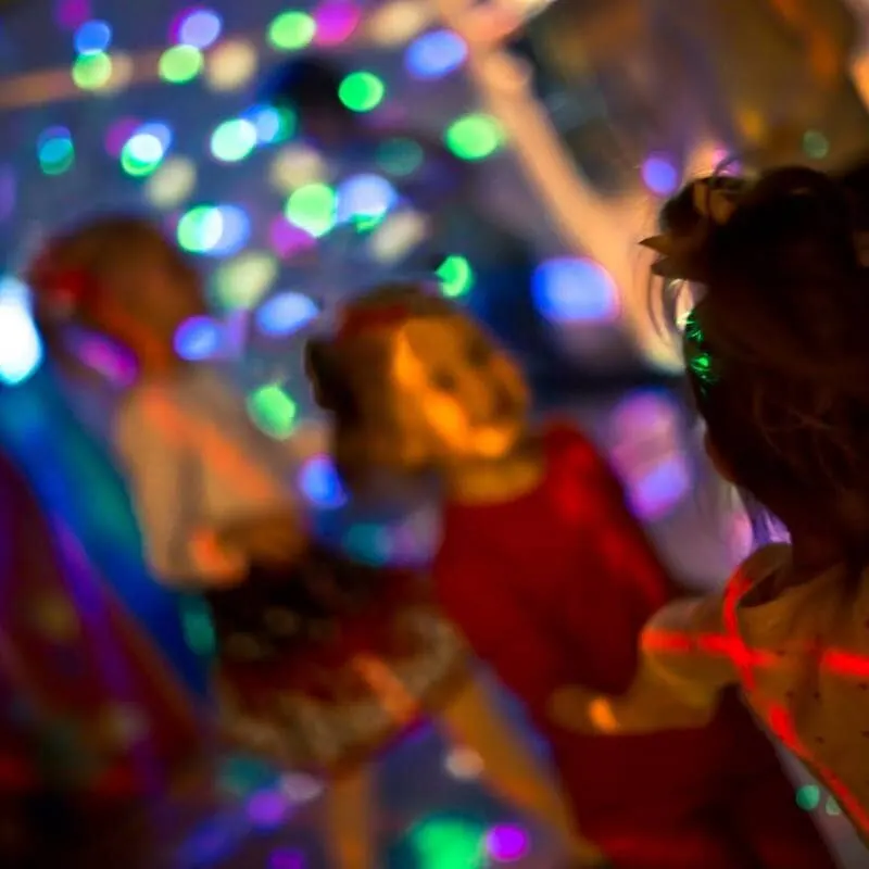People dancing at a nightclub with colourful LED lights and bokeh effects.