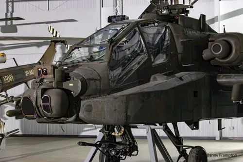 Military Apache helicopter displayed inside a hangar at an aviation museum.
