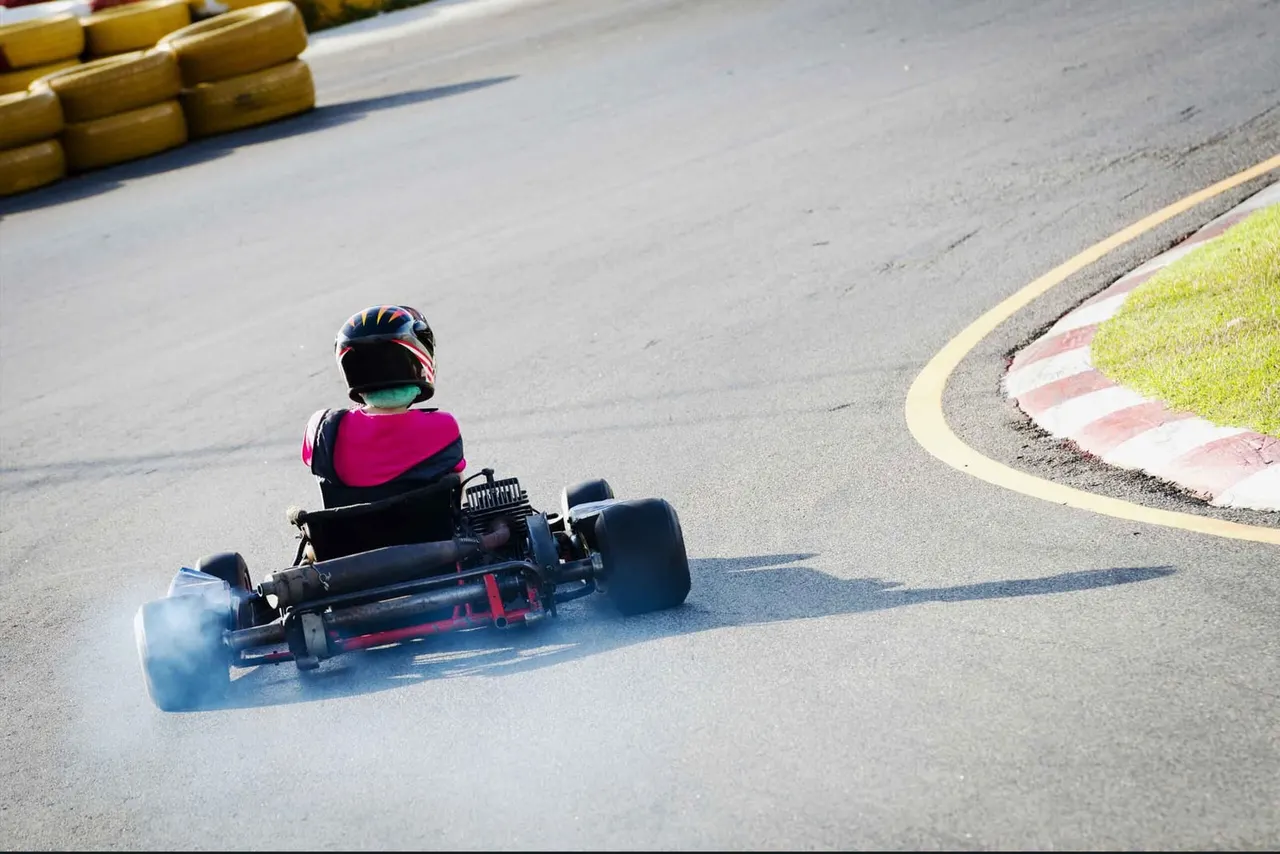 Driver in a red go-kart mid-turn on Lockwell Hill outdoor track, Farnsfield