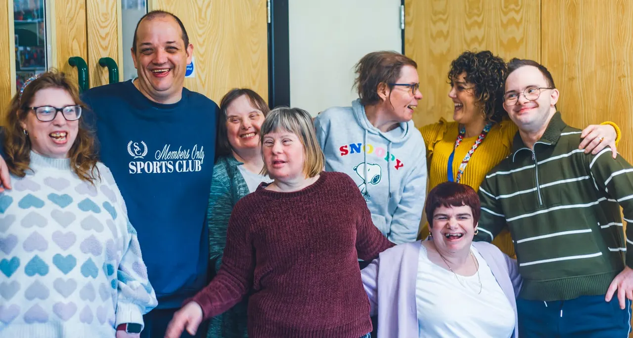 Group of eight smiling people of varying ages gathered together indoors at a leisure venue.