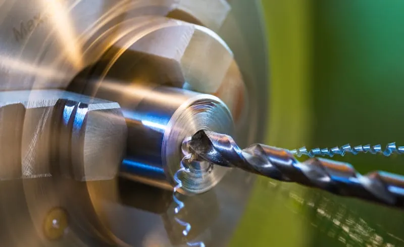 Close-up of a rotating metal lathe with a cutting tool shaping a spinning metal workpiece.