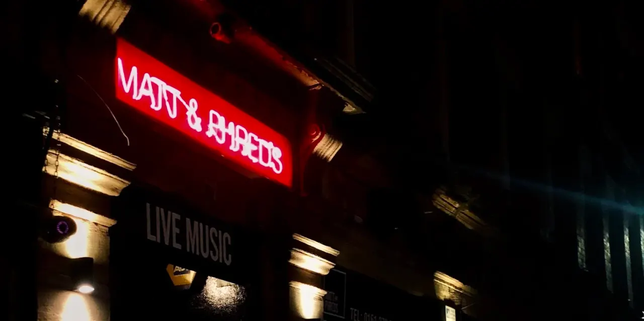 Neon sign for Matt & Phreds Jazz Club illuminated at night, with "Live Music" text visible below.