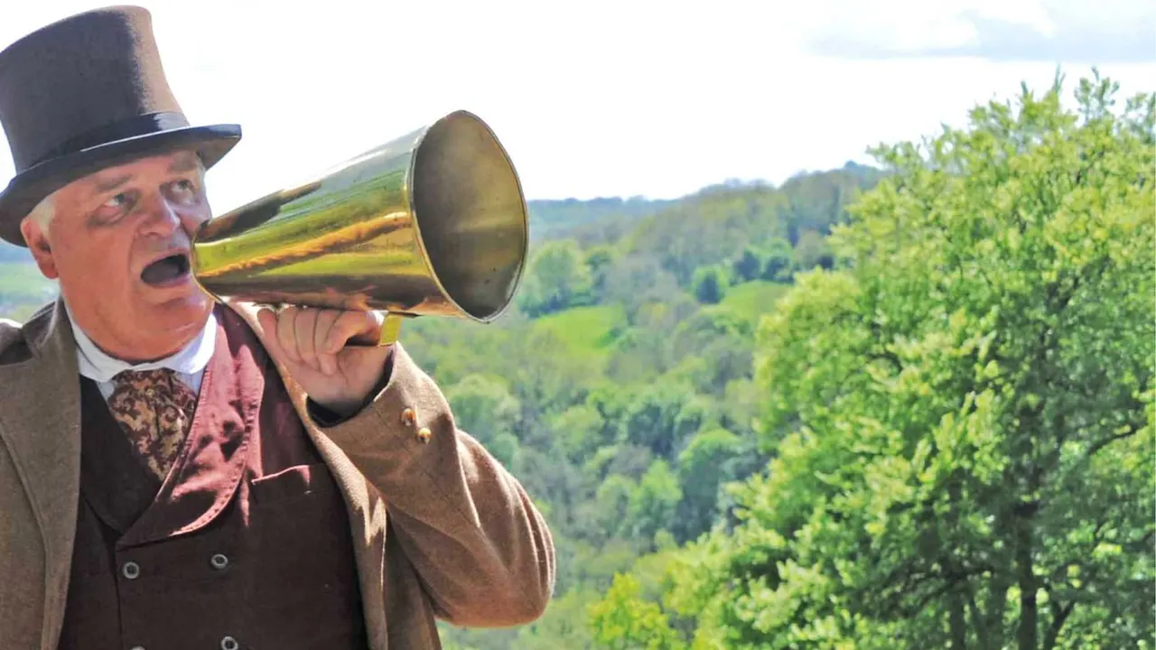 Man in Victorian costume with top hat using a brass megaphone overlooking green rolling countryside and woodland.