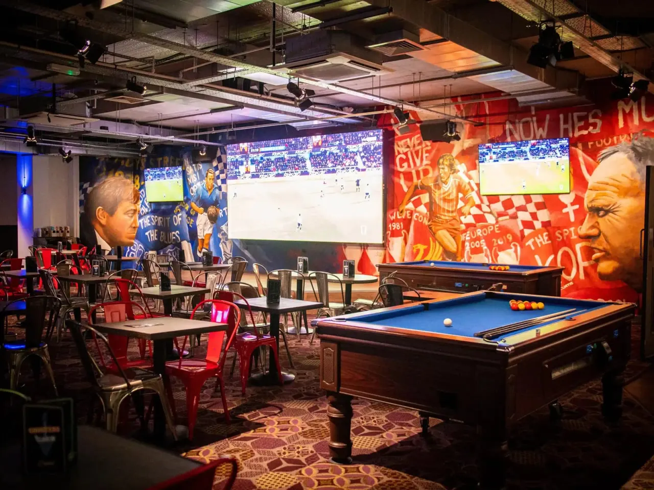Sports bar with pool table, dining tables, and multiple screens showing football matches.