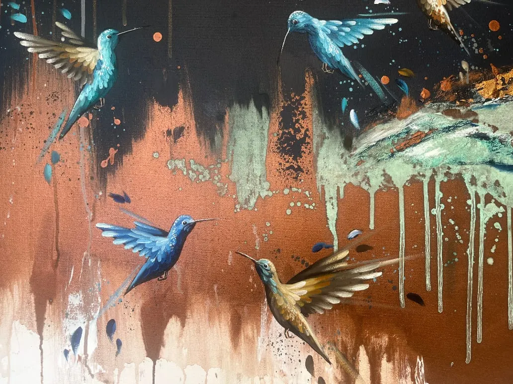 Mural artwork featuring five hummingbirds in blue and gold tones painted on a weathered rust and cream coloured wall.