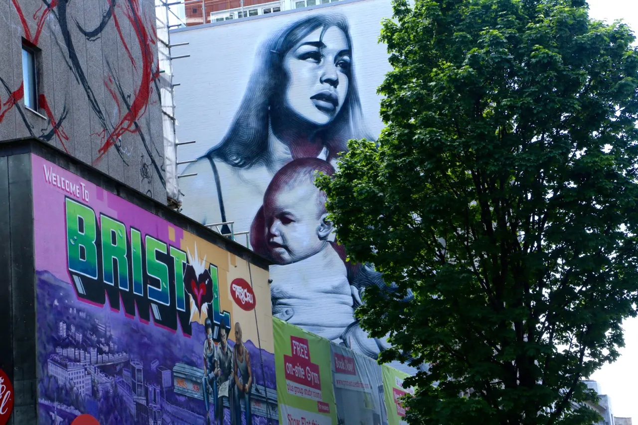 Street art mural depicting a woman and child in monochrome style on an urban building facade.
