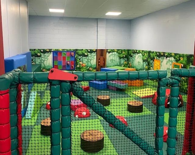 Indoor soft play facility with colorful foam obstacles, netting, and climbing structures for children.