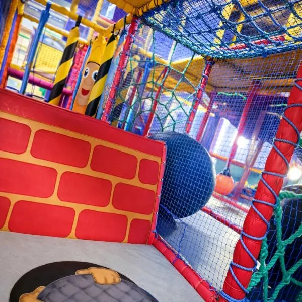 Colourful indoor play area with soft play structures, netting, and climbing equipment designed for children.