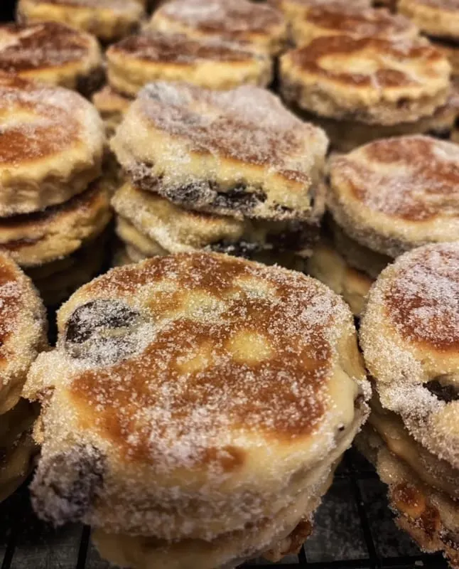 Freshly baked cinnamon and sugar-coated pastries with dark filling arranged closely together.