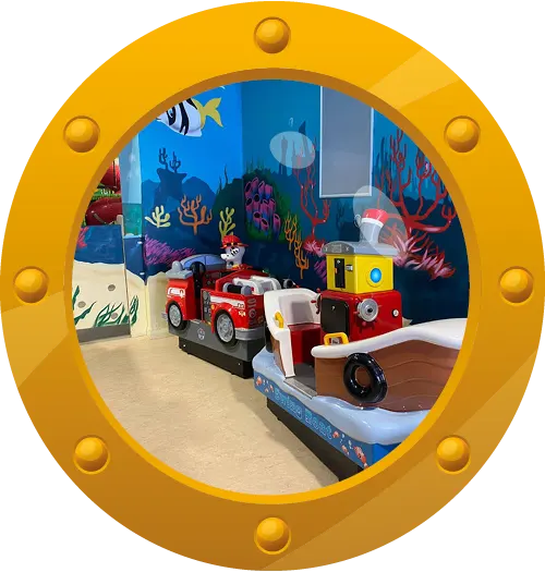 Children's play area with toy fire engine and submarine vehicles displayed against an underwater-themed backdrop.