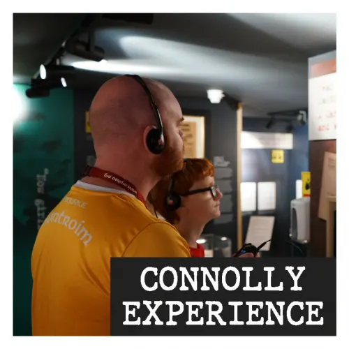 Two visitors wearing headphones stand inside the centre's exhibition space.