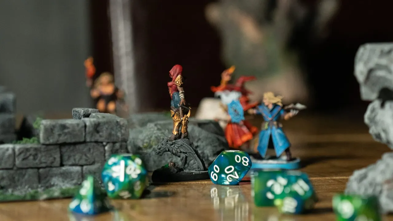 Tabletop gaming setup with painted fantasy figurines, polyhedral dice and stone terrain pieces on a wooden surface.