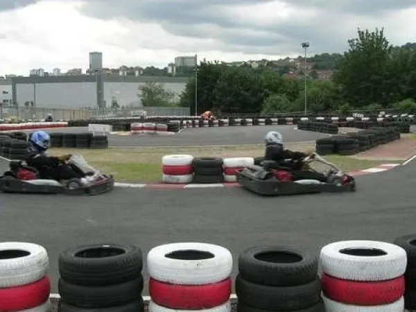 Two go-kart racers navigate a track lined with painted tyres at an outdoor karting circuit.