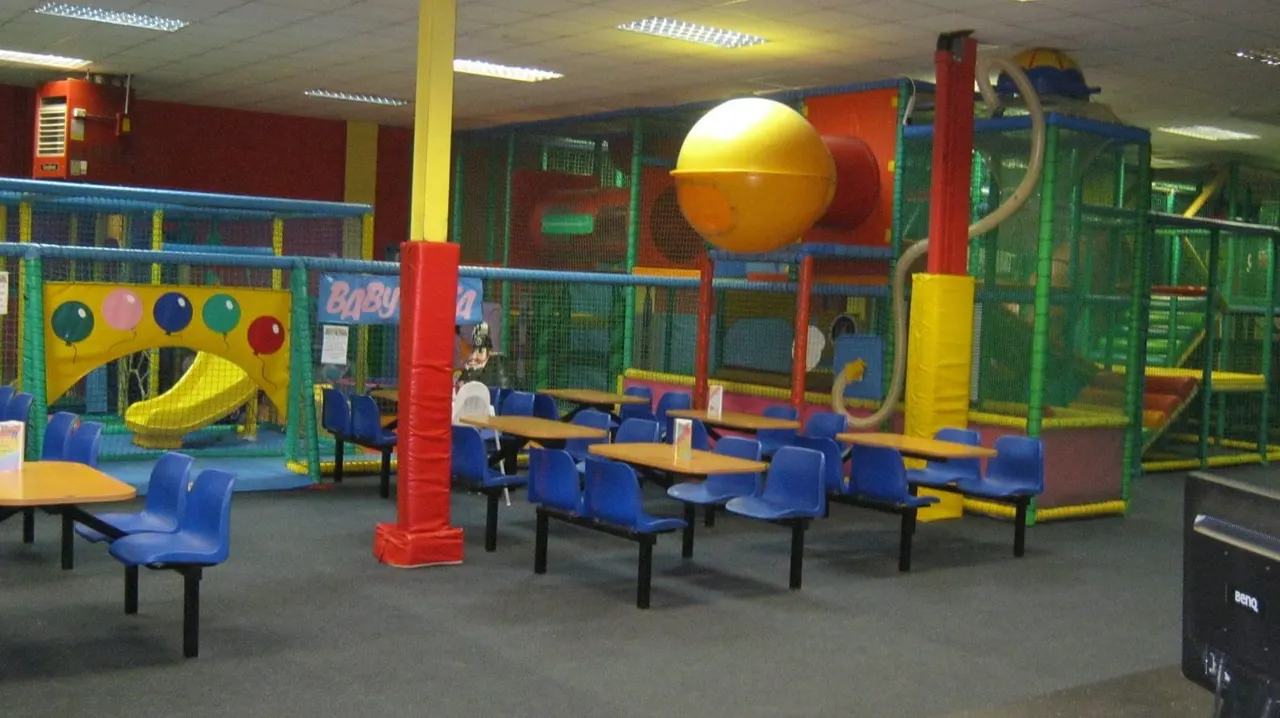 Indoor play area with colourful soft-play structures, climbing frames, and seating for parents and carers.
