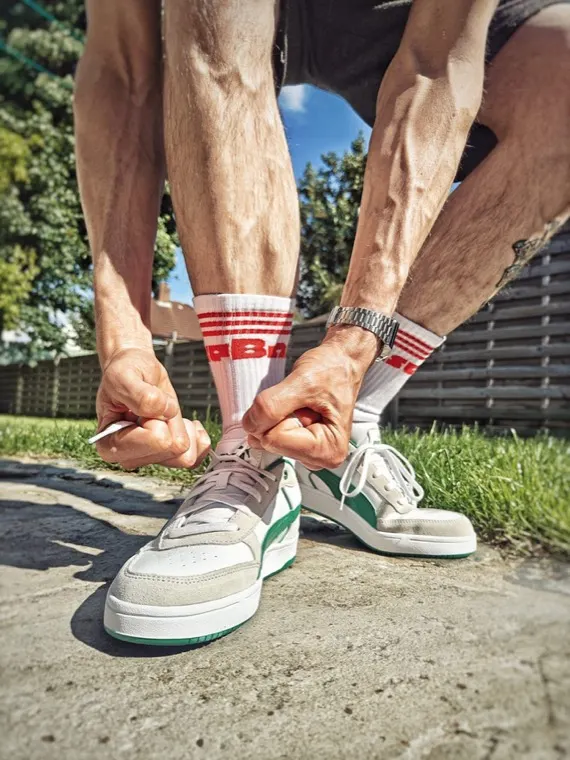 Person tying trainers before outdoor activity in a sunny garden setting.