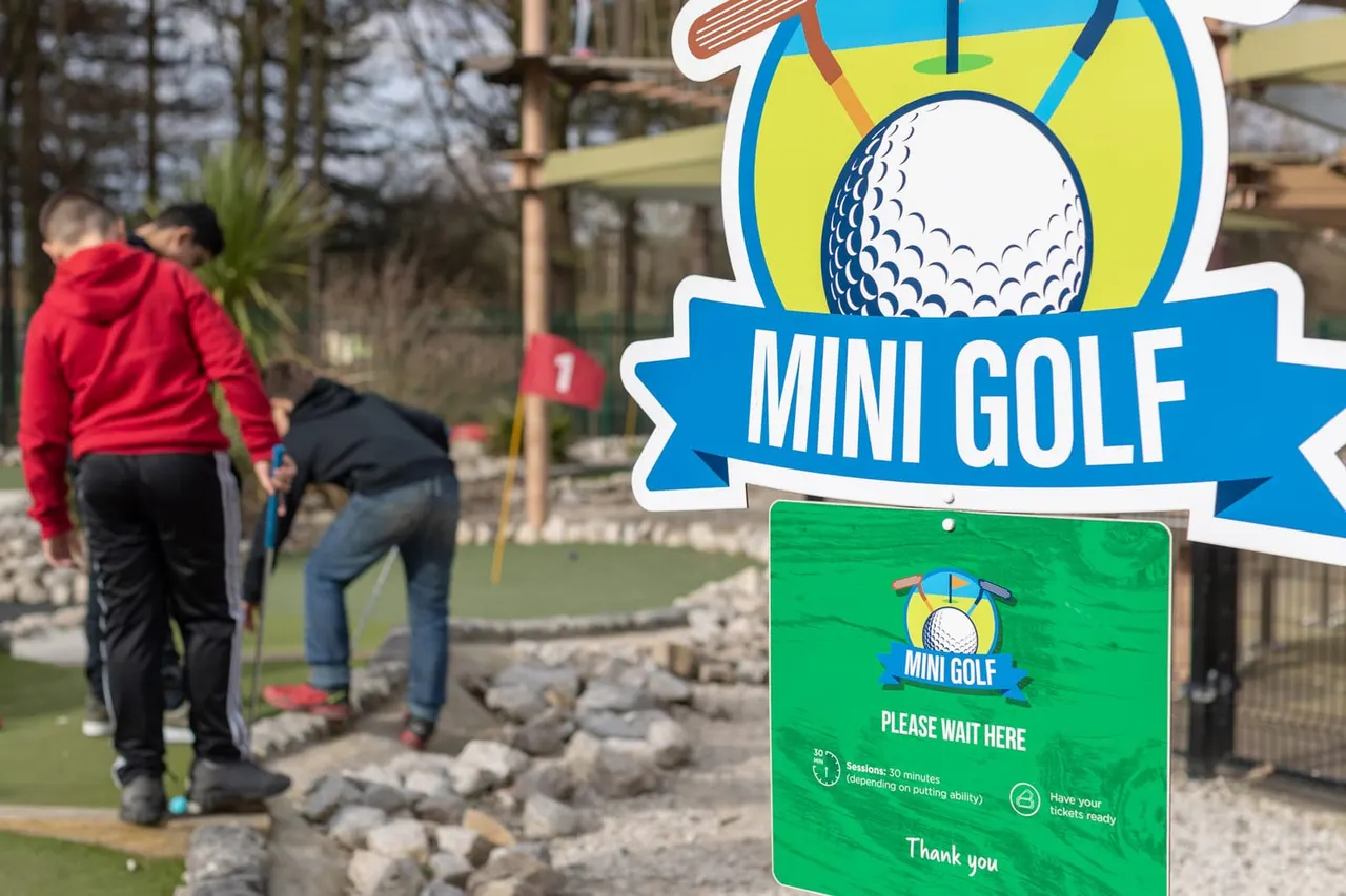Mini Golf please wait here sign and players on hole 1 at Holme Pierrepont OAZ