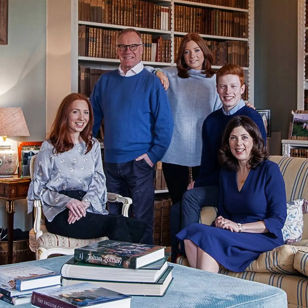 Five people pose together in a library room with bookshelves and period furnishings.