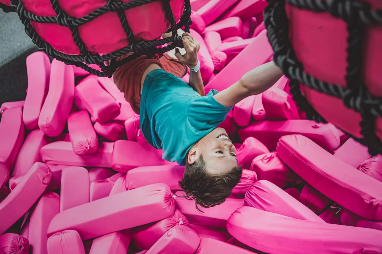 Child playing on a bright pink inflatable bouncy castle structure.