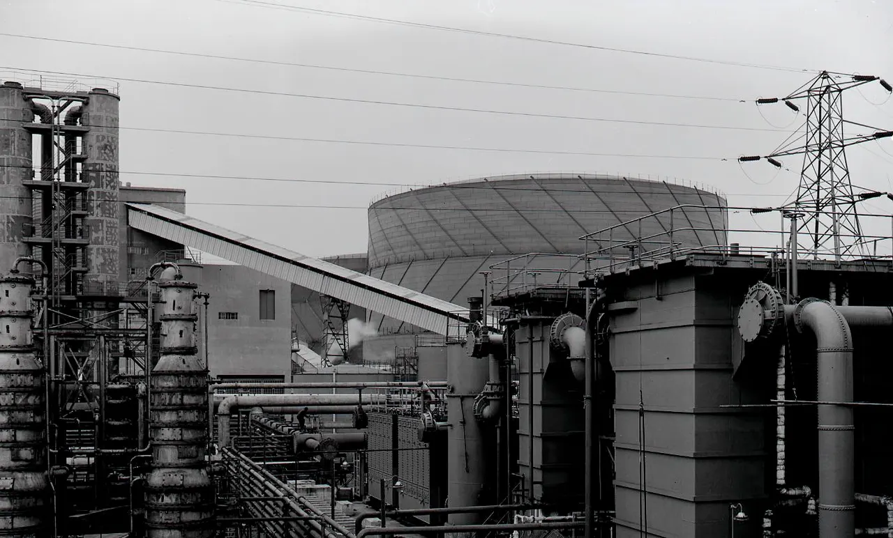Industrial gas processing plant with storage tanks, pipework, and steel infrastructure under grey sky.