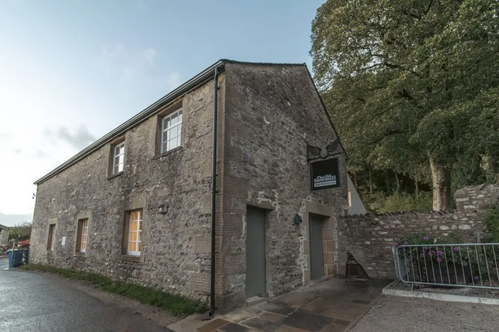 Stone building with ivy-covered walls and windows, surrounded by trees at a countryside leisure venue.