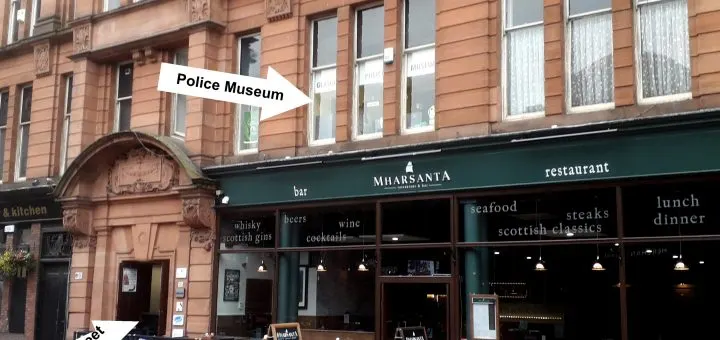 Red sandstone building with Police Museum signage above an arched doorway, with Mirasanta restaurant storefront below featuring dark green fascia.