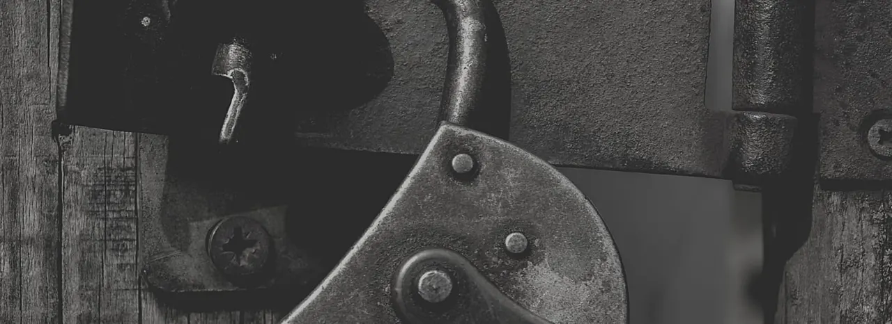 Close-up of industrial metal machinery with gears and bolts on a wooden surface.