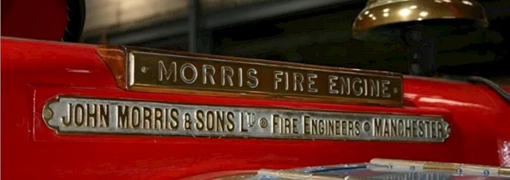 Historic red fire engine with brass manufacturer plaques reading "Morris Fire Engine" and "John Morris & Sons Ltd Fire Engineers Manchester".