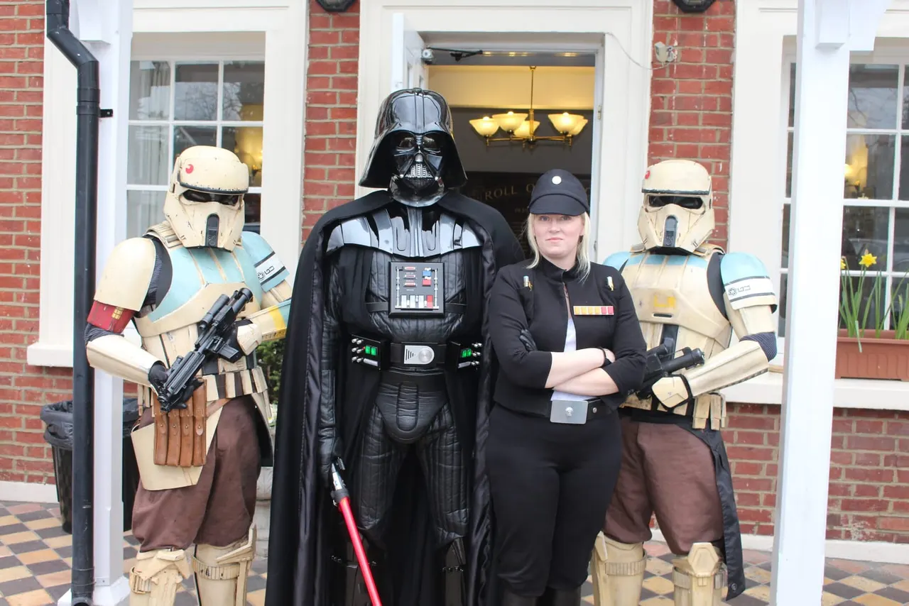 People in Star Wars costumes pose outside a brick building entrance.