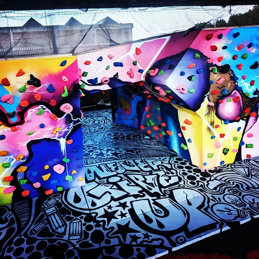 Child climbing the sheltered kids wall with multicoloured holds at Boatyard Boulders.