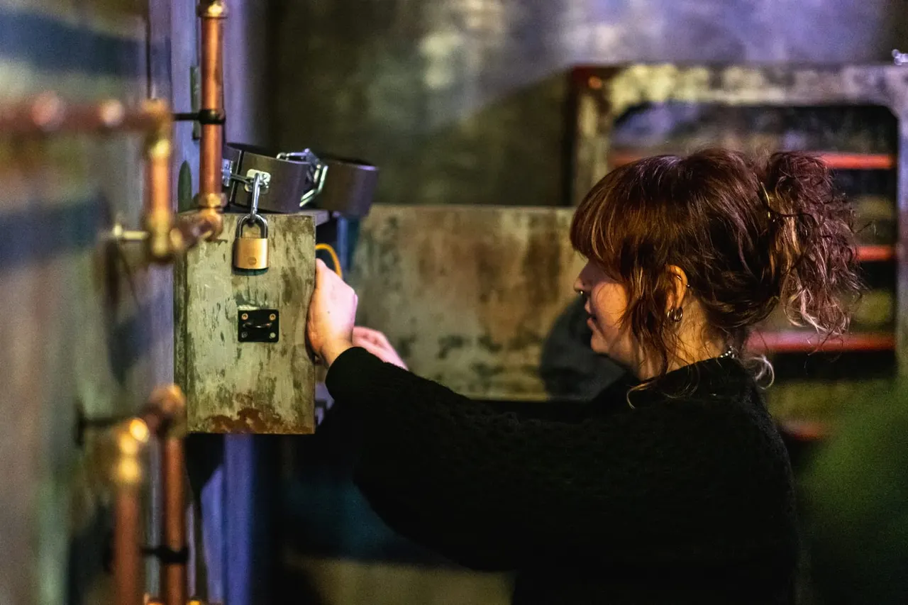 Woman attempting an escape room puzzle by unlocking a padlock on a wooden panel.