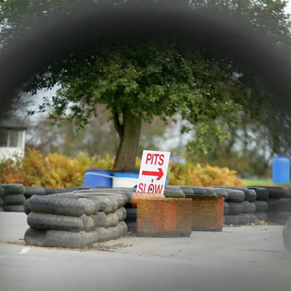 Go-kart racing track with "Pits Slow" sign, tyres and barriers marking the circuit course.