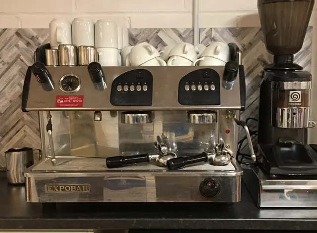 Professional espresso machine with grinder and cup storage on a counter.