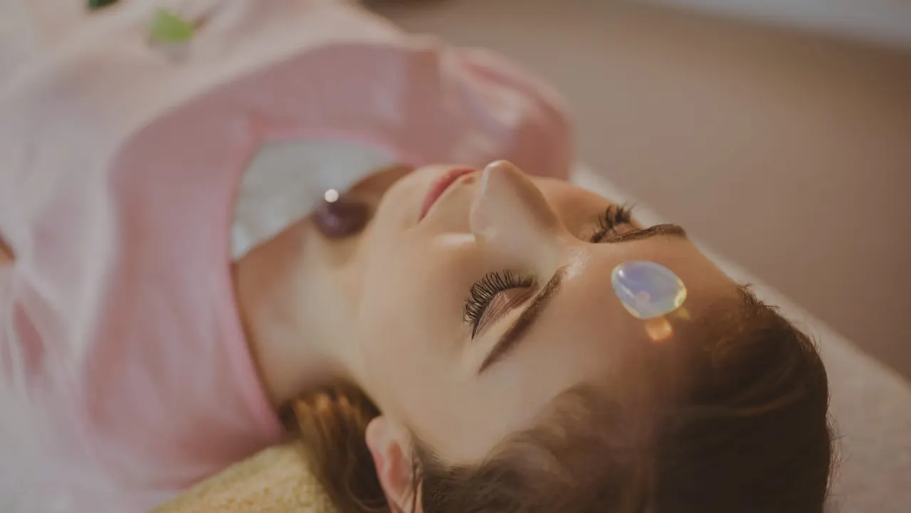 Woman relaxing during a spa facial treatment with eyes closed and protective pads on eyelids.