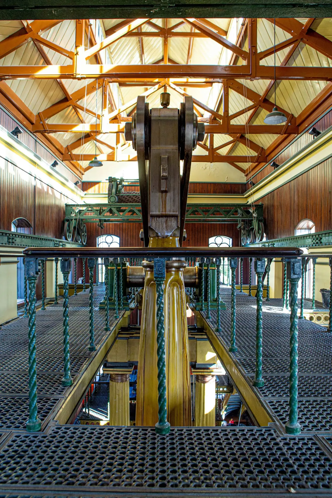 Interior of a historic Victorian engine house with cast-iron machinery and wooden roof trusses.