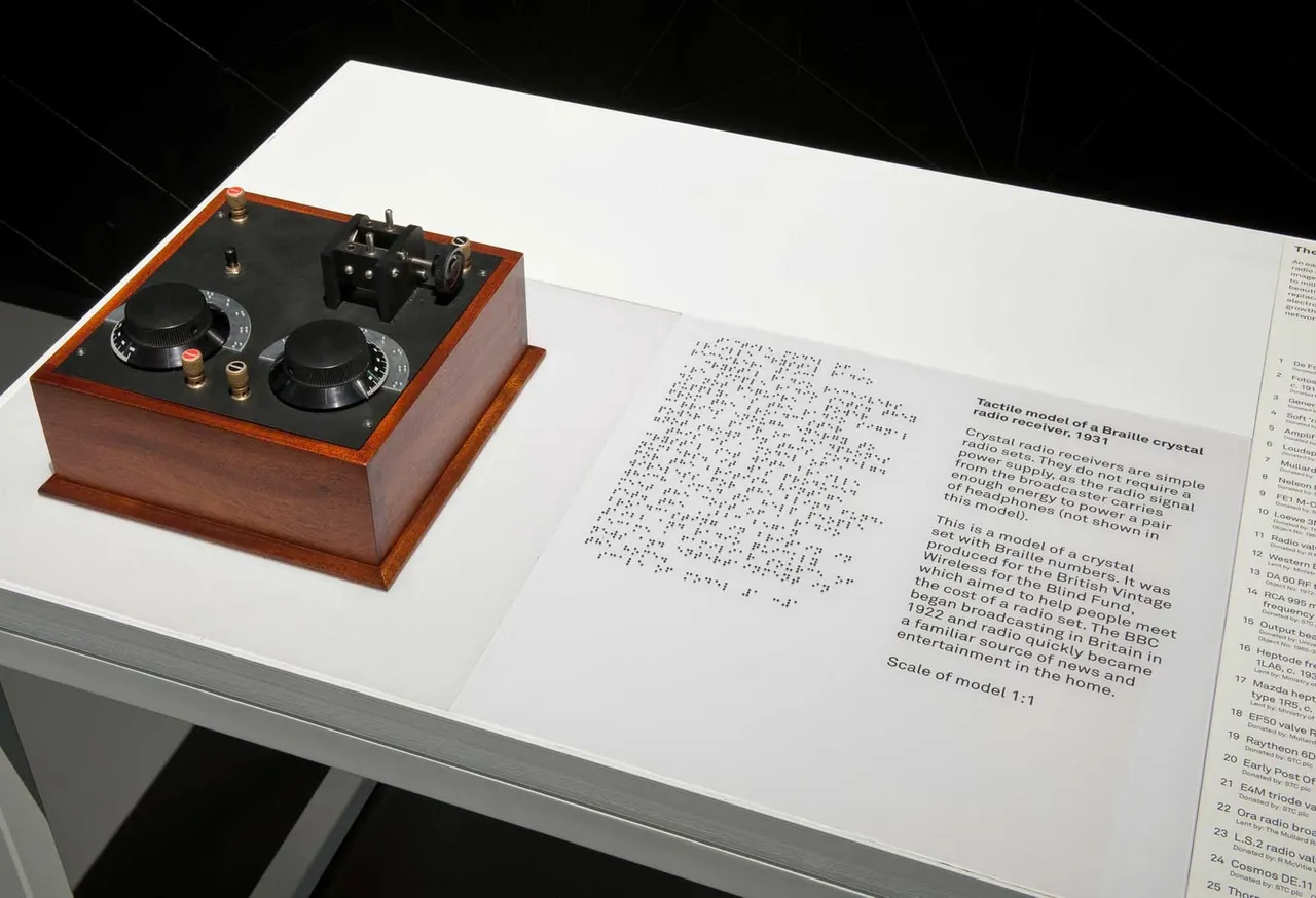 Tactile model of a Braille crystal radio receiver with wooden base and control knobs, displayed alongside informational text.