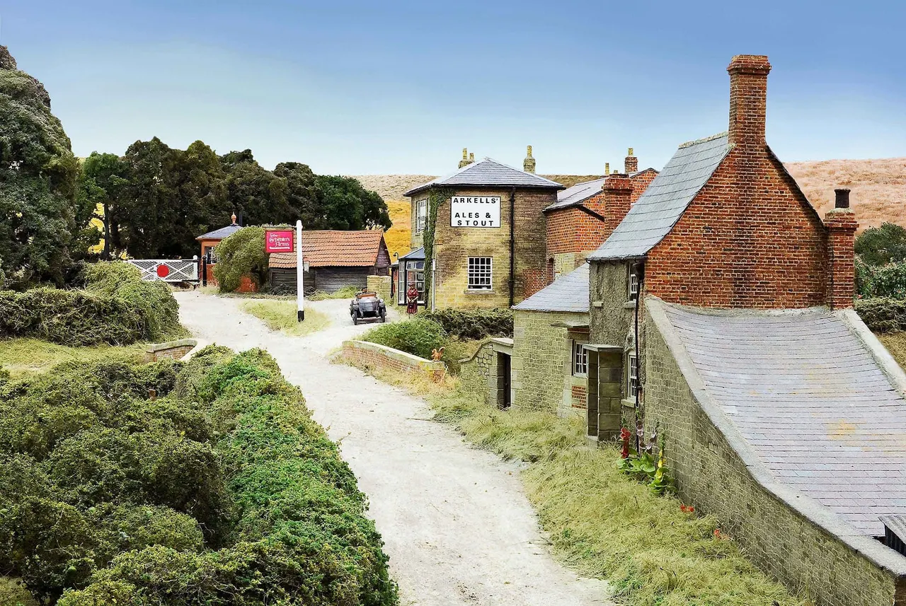 Historic brick buildings with slate roofs set in a rural landscape, featuring signage for Arkells Ales and Stout, surrounded by trees and hills.