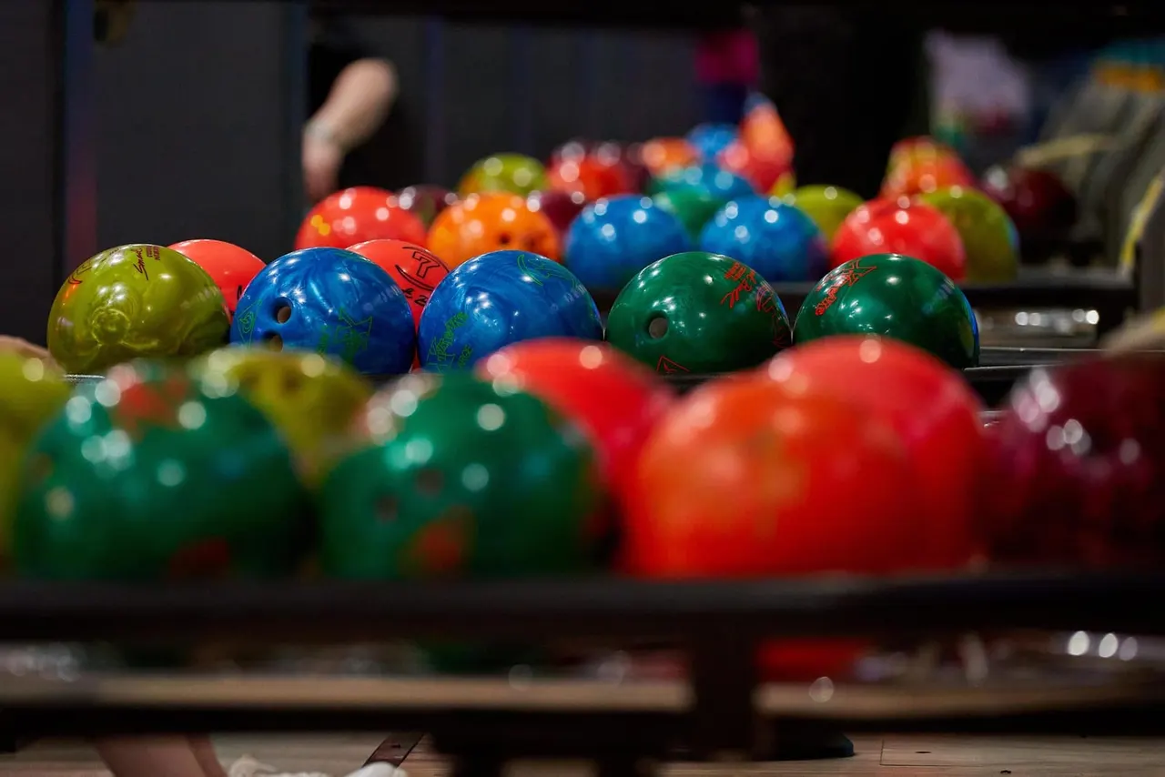 Colourful bowling balls lined up on the ball return at a bowling alley.