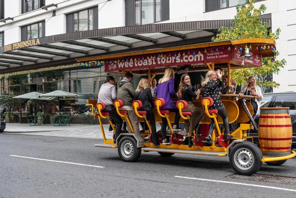 A group of tourists ride together on a yellow pedal-powered tour vehicle on an urban street.