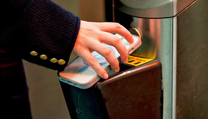 Person's hand pressing a hand sanitiser dispenser on a wall.